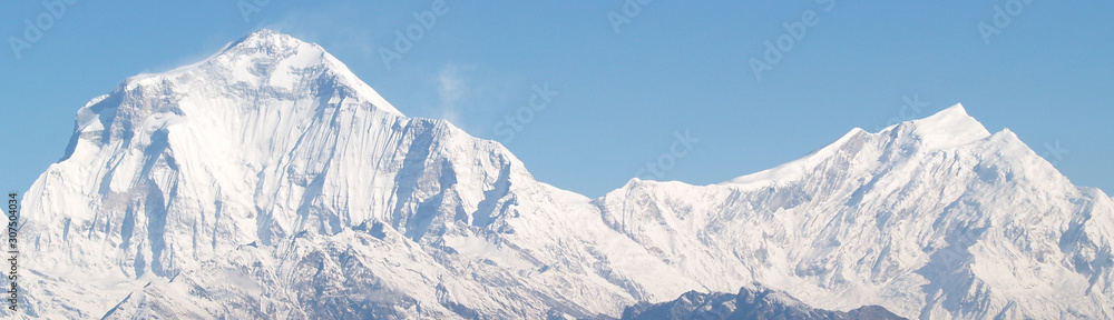 Amazing autumn panorama with mountains covered with snow and forest against the background of blue sky and clouds. Mount Everest, Nepal.