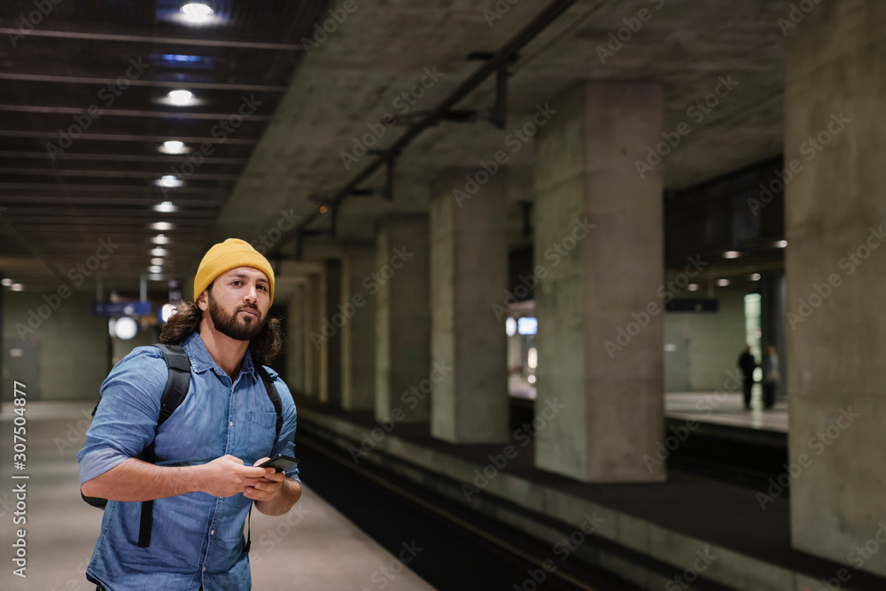 Portrait of man with smartphone waiting at platform, Berlin, Germany Portrait of man with smartphone waiting at platform, Berlin, Germany