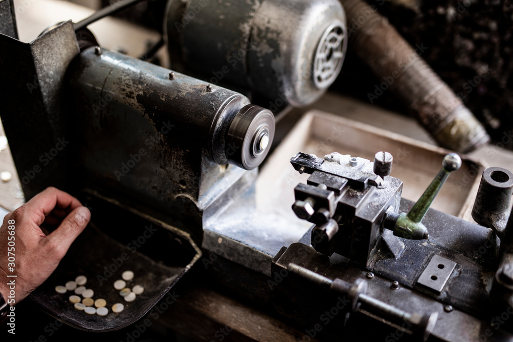 Cropped hand of worker making buttons with equipment in workshop Cropped hand of worker making buttons with equipment in workshop