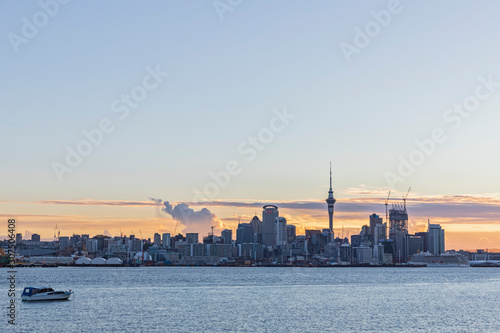 Modern buildings and Devonport by sea against cloudy sky in Auckland, New Zealand photo