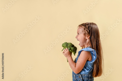 Healthy food, freshly vegetables, cute girl on an orange background in the studio. happy kid girl eating healthy food vegetables at home in nursery.