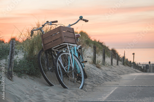 Netherlands, South Holland, Noordwijk, bicycles on sandy beach at sunset