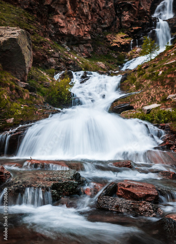 Waterfall in Gran Paradiso Italian alps mountains in Graian Alps in Piedmont, Italy with snow capped peaks.