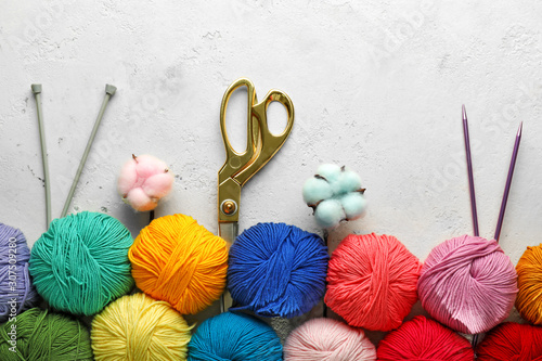 Knitting yarns, scissors and needles on light background