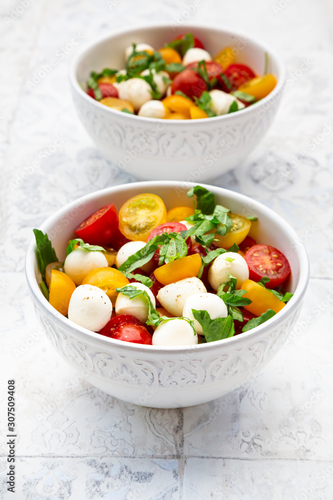 Two bowls of fresh salad lying on tiled table Two bowls of fresh salad lying on tiled table