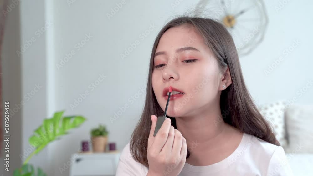 Beautiful Asian women make up themselves by using a brush to apply lipstick to their lips. Beautiful Asian women make up themselves by using a brush to apply lipstick to their lips.