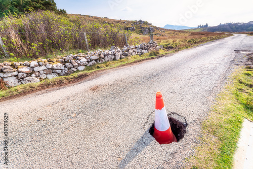 Traffic cone in pot hole on road at Isle of Skye, Highlands, Scotland, UK photo