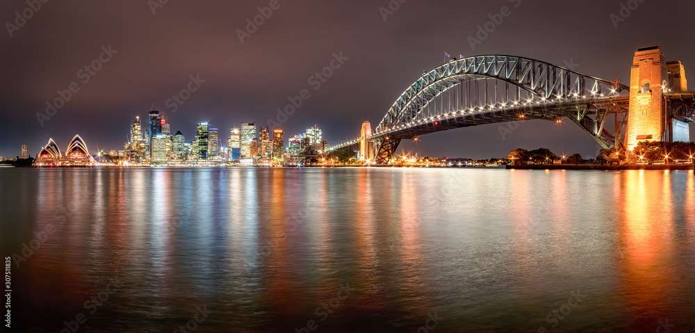 Panoramic shot of illuminated Sydney Harbor Bridge over river against sky at night, Sydney, Australia Panoramic shot of illuminated Sydney Harbor Bridge over river against sky at night, Sydney, Australia
