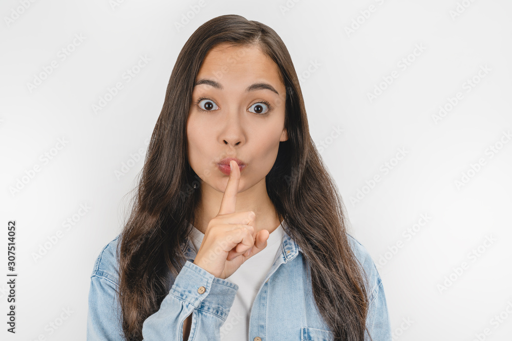Positive young woman showing silence gesture isolated over white background Positive young woman showing silence gesture isolated over white background
