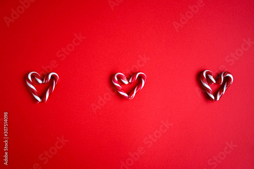 Red candy canes on red background. Hearts made out of sugar candy canes. Christmas, holiday concept. Red colour only