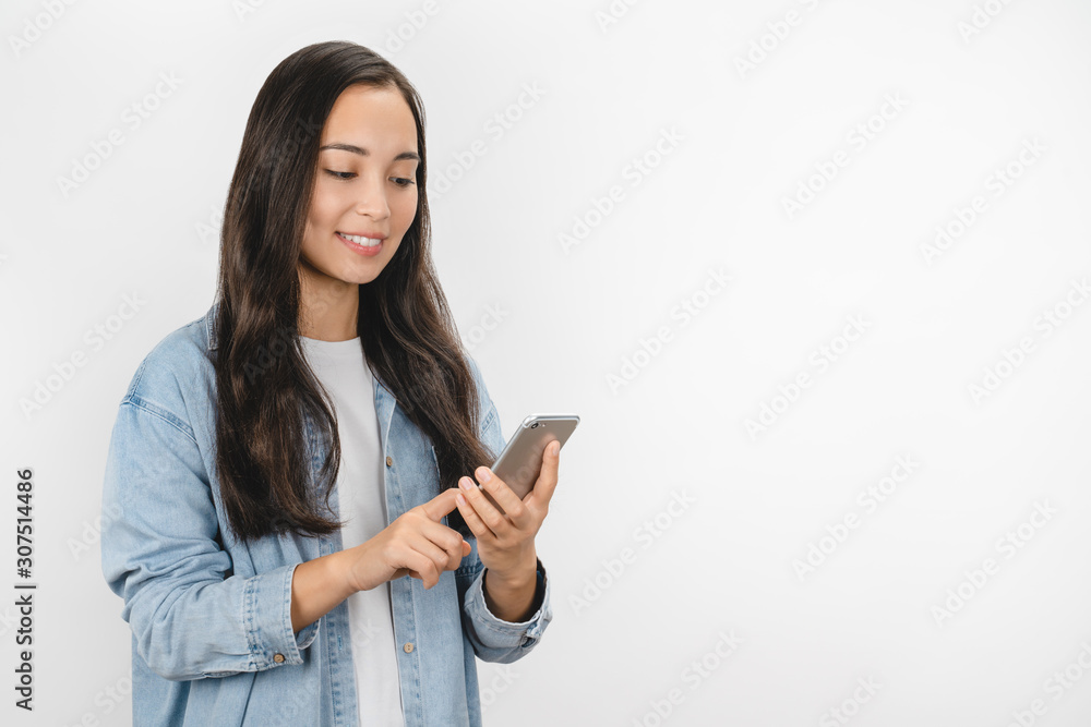 Portrait of smiling casual asian woman holding smartphone over white background Portrait of smiling casual asian woman holding smartphone over white background