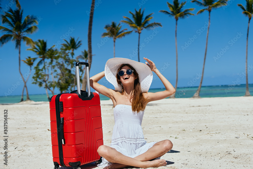 girl on the beach with suitcase and hat
