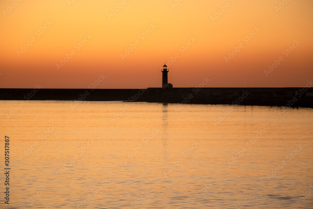 Lighthouse at sunset in Douro River estuary, Porto, Portugal. Golden hour