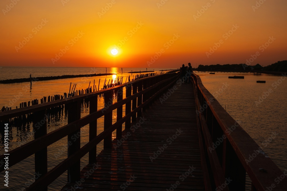 wooden pier at the sea with beautiful bloody sunset.  sunset seascape at a wooden jetty. Wood bridge
