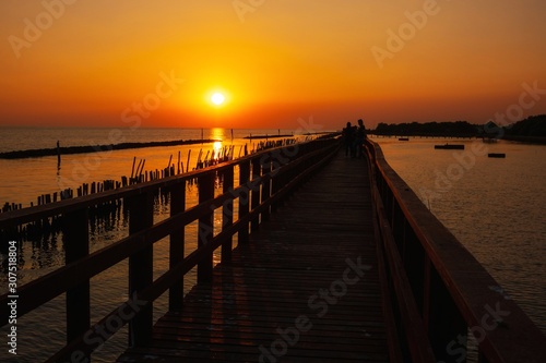 wooden pier at the sea with beautiful bloody sunset. sunset seascape at a wooden jetty. Wood bridge