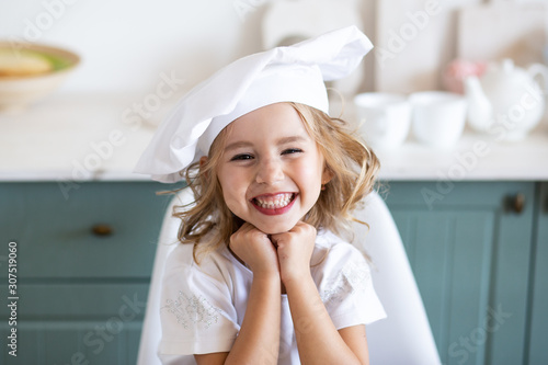 smiling cute girl in a chefs toque in kitchen