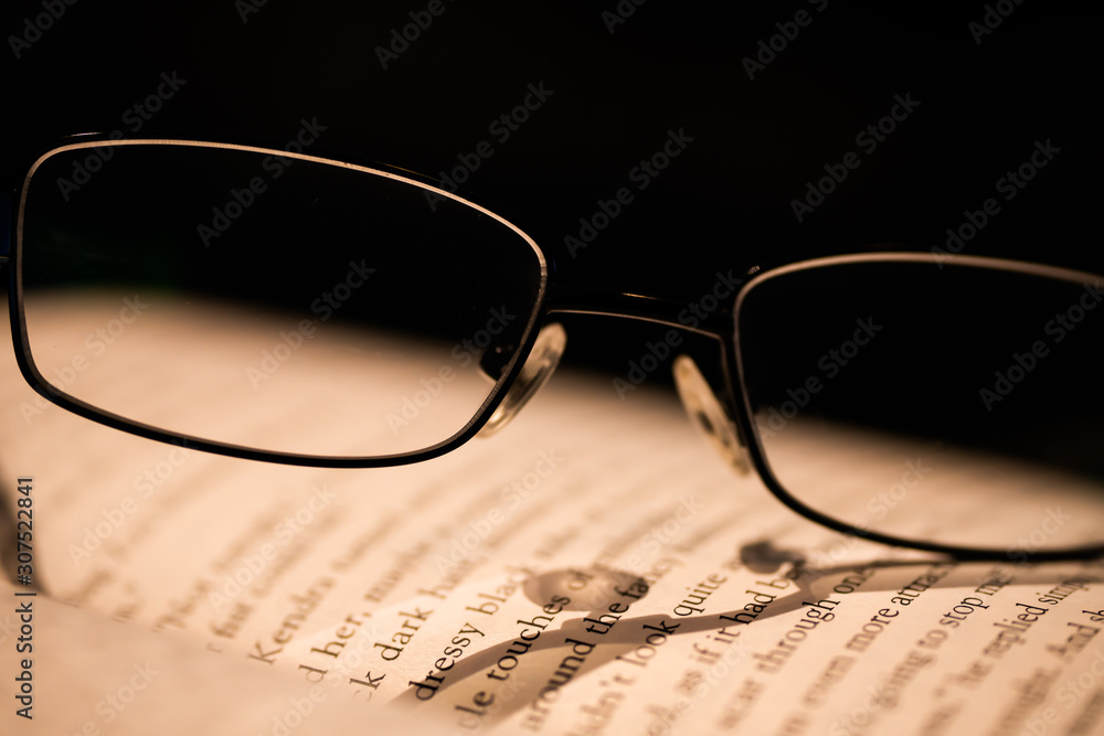 closeup of glasses stacked on an open book closeup of glasses stacked on an open book