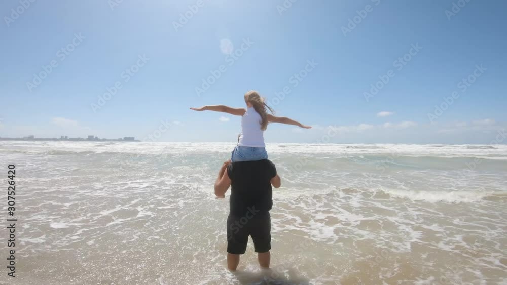 Happy father and daughter play on the beach during a sea storm. Concept of friendly family, travel, lifestyle. Happy father and daughter play on the beach during a sea storm. Concept of friendly family, travel, lifestyle.