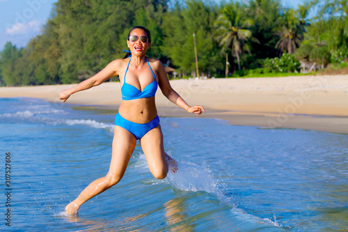 Woman pretty with bikini blue jump on wave at beach