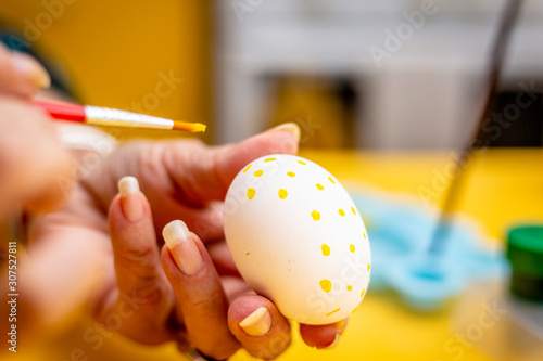 Woman painting with brush a easter eggs.