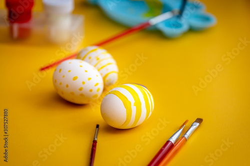 White easter egg with yellow dots and line painted with brush.