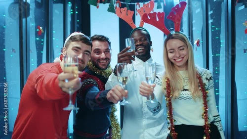 In modern data center, beautiful group of happy co-workers in holiday mood toasting with drinks celebrating corporate party on Christmas. New Year holiday event. photo