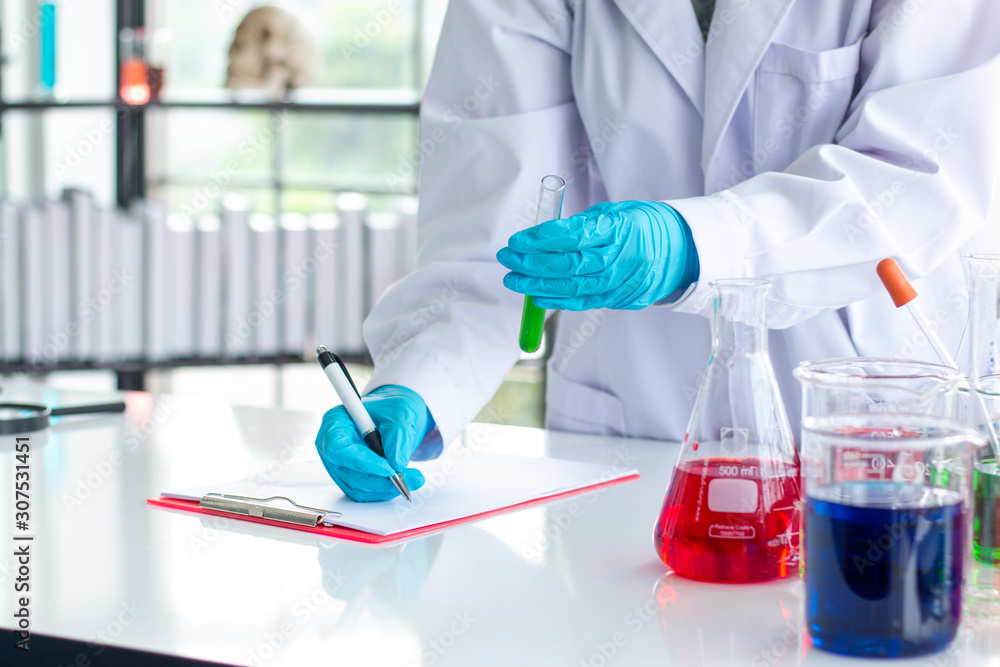 Fototapeta premium Scientists are recording results in glass bottles on a notebook.