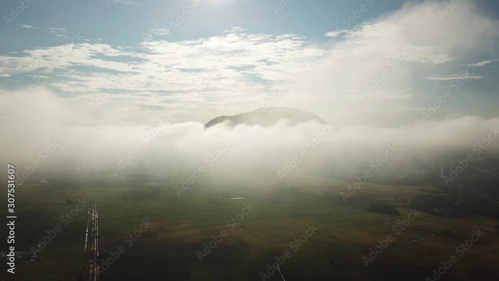 Aerial white cloud moving in morning over the mountain and green paddy field at Penang, Malaysia. Aerial white cloud moving in morning over the mountain and green paddy field at Penang, Malaysia.