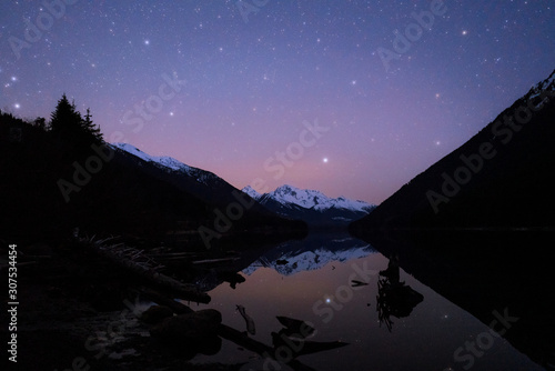 Night starry sky reflecting in calm lake in wilderness Canada
