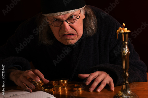 Old Scrooge busy counting his gold coins beside a candle