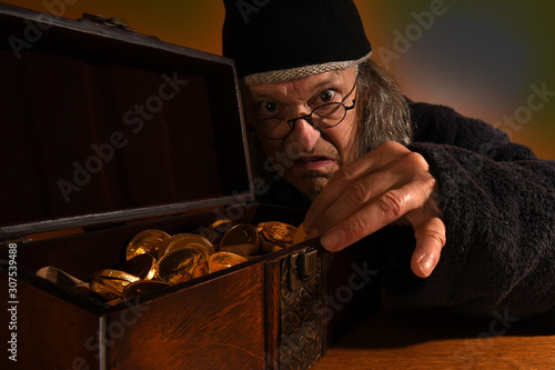 Old Scrooge making sure his gold coins are safe photo