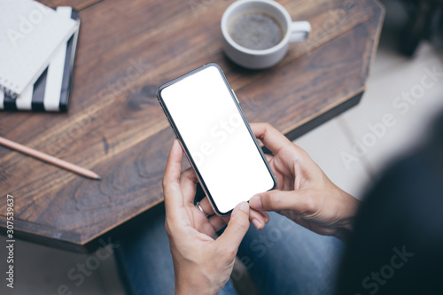 Mockup image blank white screen cell phone.men hand holding texting using mobile on sofa at home office. background empty space for advertise text.people contact marketing business and technology 