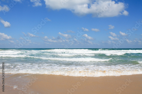 Sea foam on the sandy beach at Bat Yam  Israel. Waves on the blue stormy sea. Mediterranean coastline. Travelling picture. Turquoise water and sandy beach