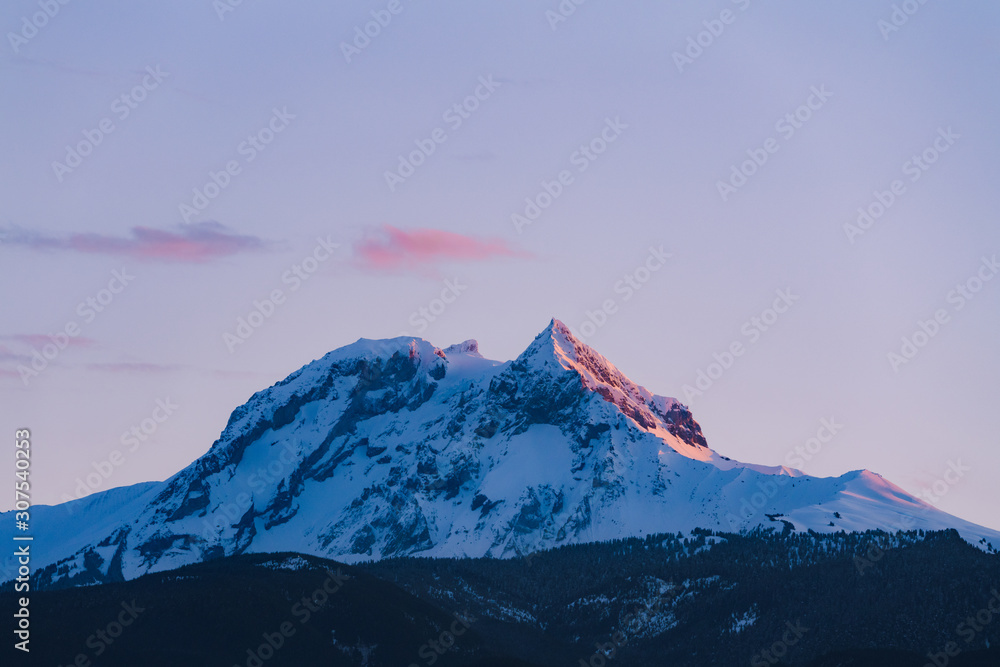 Mount Garibaldi covered in snow with last sun ray during red sunset in winter