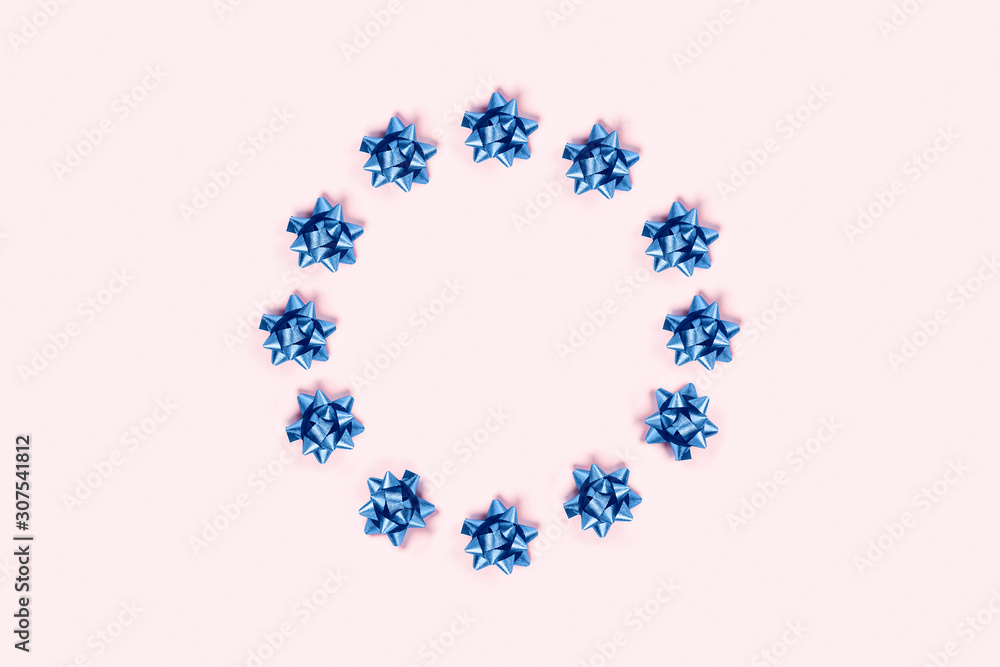 Christmas pink background with circle frame of blue bows.