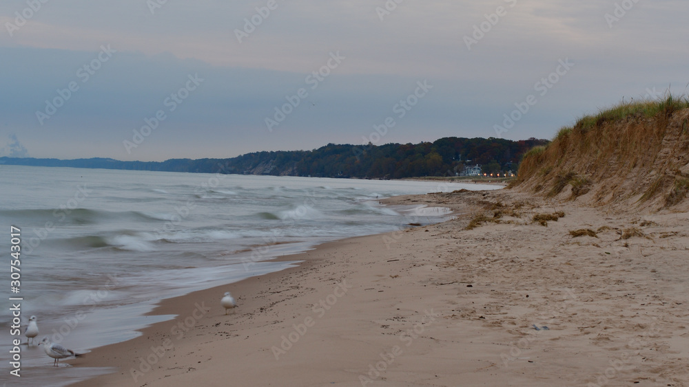 Photo of a sandy Lake Michigan beach and shoreline on a cloudy day with small waves and surf Photo of a sandy Lake Michigan beach and shoreline on a cloudy day with small waves and surf