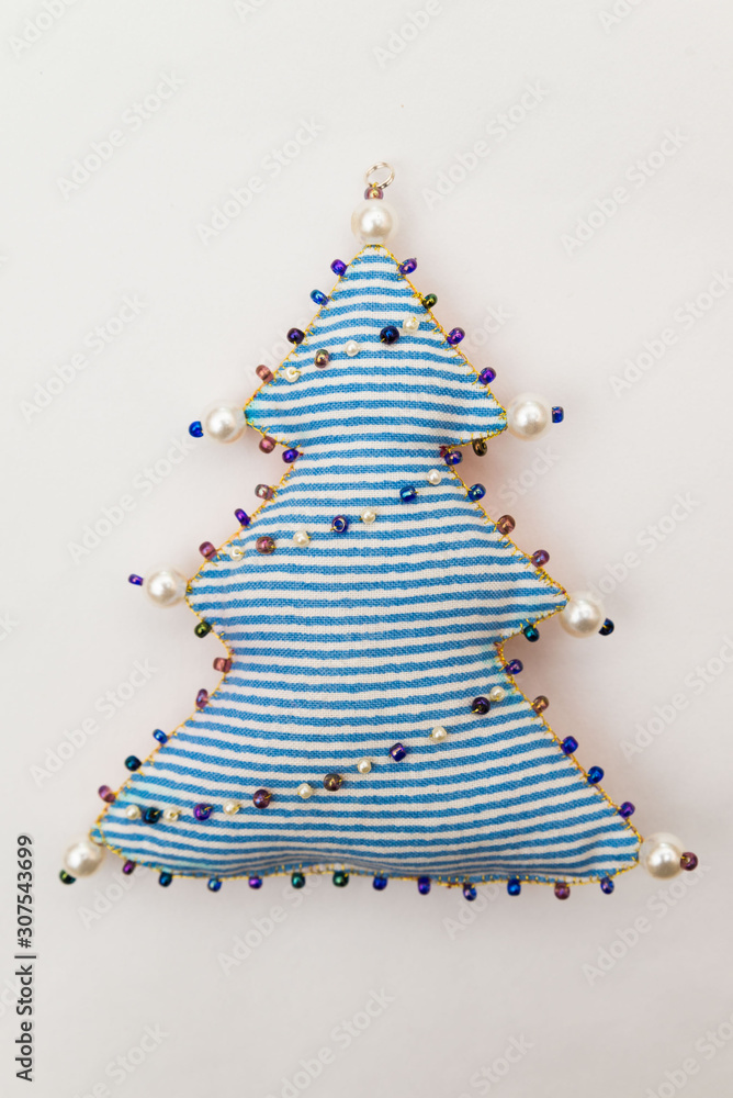 Handmade textile fabric naive blue striped retro style Christmas tree ornament decorated with beads on white background Handmade textile fabric naive blue striped retro style Christmas tree ornament decorated with beads on white background