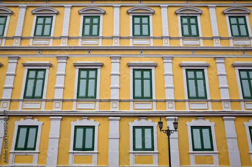  Row of blue windows on a yellow wall.