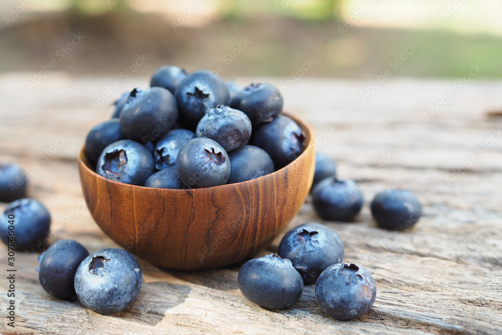 Fresh blueberries in wooden bowls on old wooden table background Fresh blueberries in wooden bowls on old wooden table background