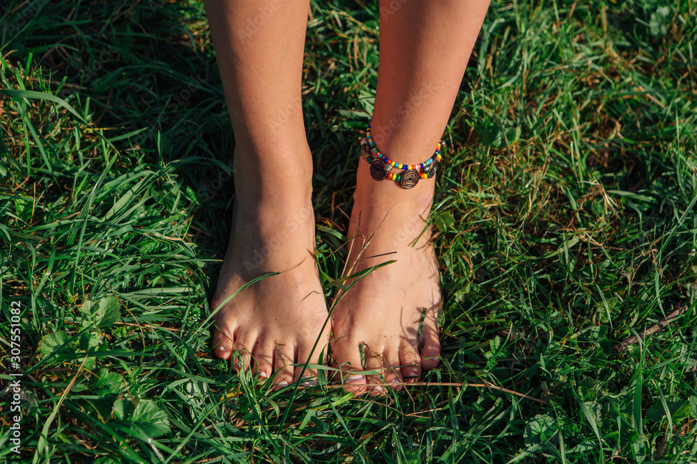 Bare woman's feet with bracelet on the grass