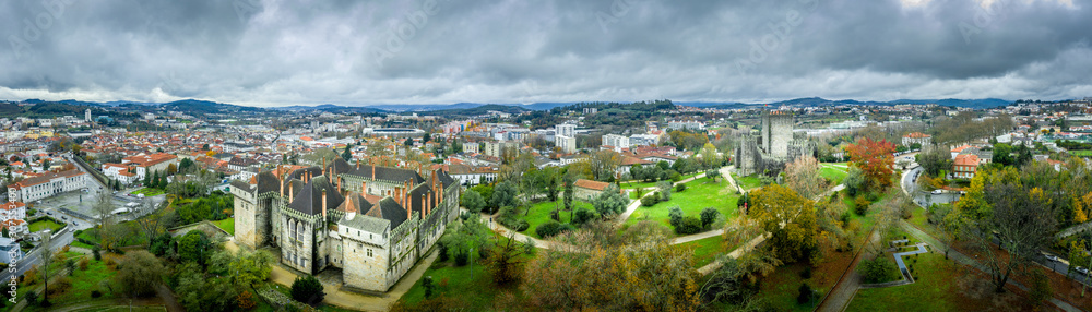 Aerial view of well-preserved medieval buildings hilltop, 10th-century Guimarães Castle with its sweeping city views. Restored Dukes of Bragança Palace, Romanesque São Miguel do Castelo Church