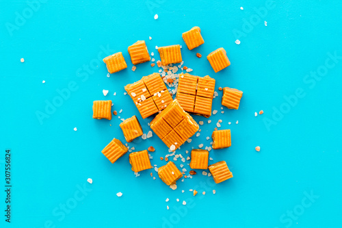Fotografi Salted caramel pieces - paradoxical sweets - on blue background top view frame