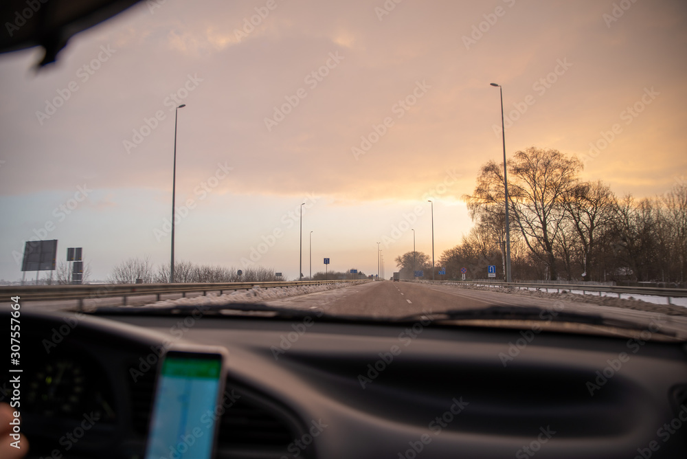 car travel concept sunrise at winter highway navigation on phone