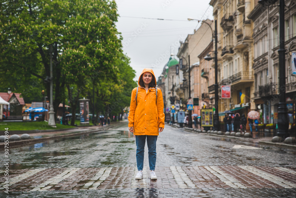 woman in the middle of the street crossing road in yellow raincoat