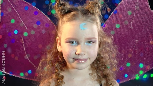 Close-up portrait of a cute fairy girl in a magic outfit looking at the camera at the christmas party.