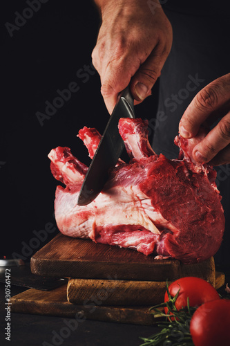 Male butcher cuts raw beef meat.