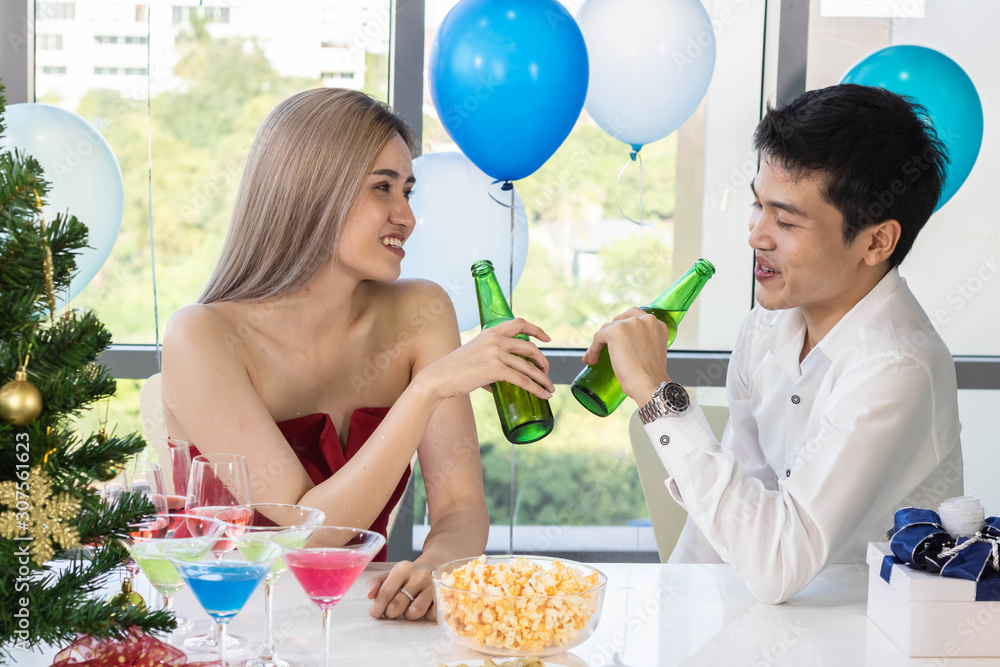 Young couple celebrating new year together, drinking beer together.