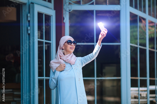 Muslim business woman taking a selfie on a smartphone .