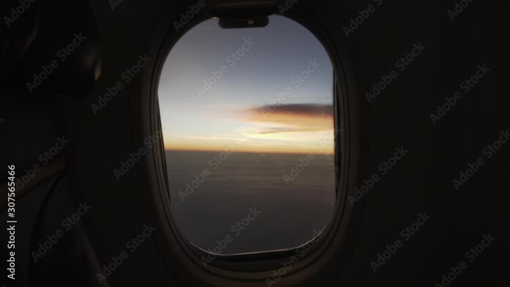 View of beautiful sunrise or sunset from a commercial plane window then push in dolly to the window to see the clouds and sky while the plane turns. View of beautiful sunrise or sunset from a commercial plane window then push in dolly to the window to see the clouds and sky while the plane turns.