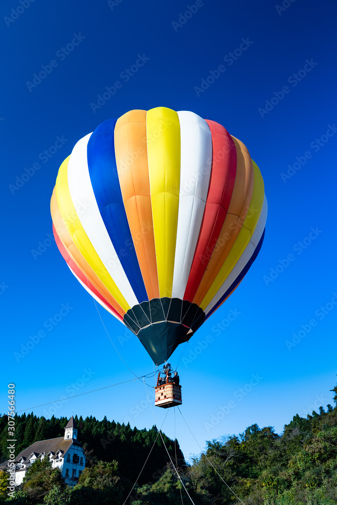 Naklejka premium Balon na ogrzane powietrze zacumowany na czystym niebie wczesnym rankiem